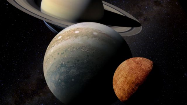 A detailed artistic depiction shows three celestial bodies aligned in space. A large, ringed gas giant is in the background, a rocky planet with noticeable storm systems is in the middle, and a small, potato-shaped moon or asteroid is in the foreground against a backdrop of distant stars. Opens a new window with the video.