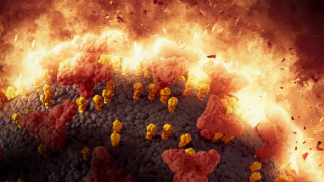 Illustration of a microscale event showing large gray spheres covered in smaller yellow and red structures, amidst an intense fiery backdrop with bursts of flames and glowing particles. Opens a new window with the video.