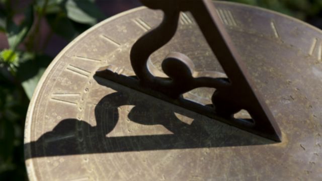 Close-up of a sundial with a triangular gnomon casting a shadow on a brass plate, which is intricately engraved with symbols associated with the Mazzaroth. Opens a new window with the video.