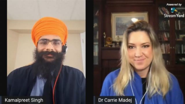 A split-screen video conference image showing two speakers. On the left, a man with a beard and a bright orange turban, identified as Kamalpreet Singh, wearing headphones; on the right, a woman with blonde hair, identified as Dr. Carrie Madej, also wearing headphones. Both are smiling and appear engaged in a discussion. Opens a new window with the video.