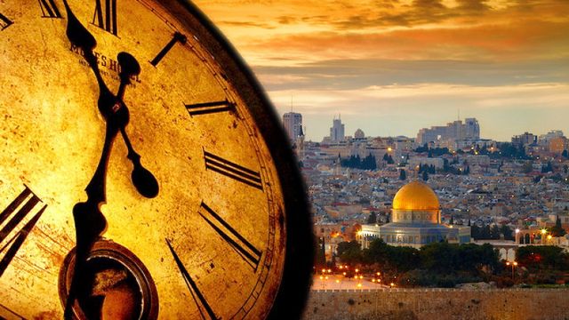 A large vintage clock showing approximately six o'clock blends into a cityscape at sunset, featuring prominent historical and modern buildings under a golden sky. Opens a new window with the video.