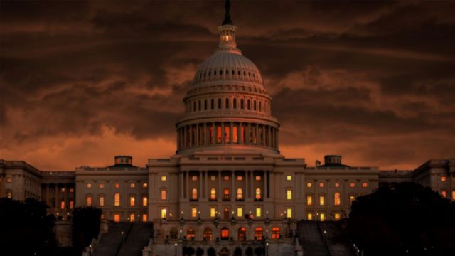 A dramatic view of the United States Capitol Building at twilight with fiery twilight hues and a scattering of clouds, the building's classical architecture illuminated by warm interior lights. Opens a new window with the video.