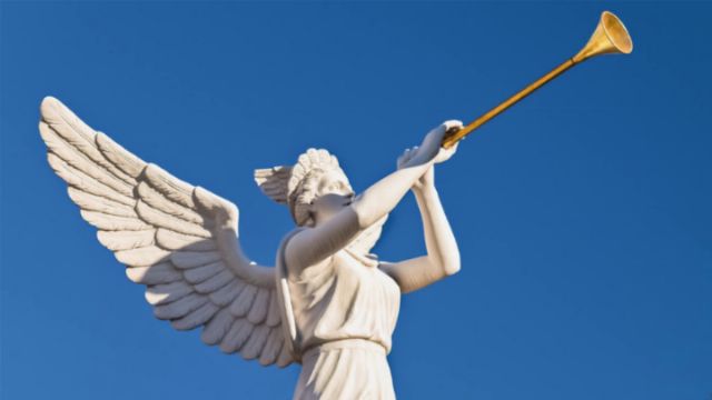 A white marble sculpture of an angel with extended wings, blowing a long trumpet against a clear blue sky. Opens a new window with the video.