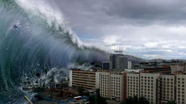 A digitally manipulated image showing a colossal wave crashing over a coastal city under stormy skies. Opens a new window with the video.
