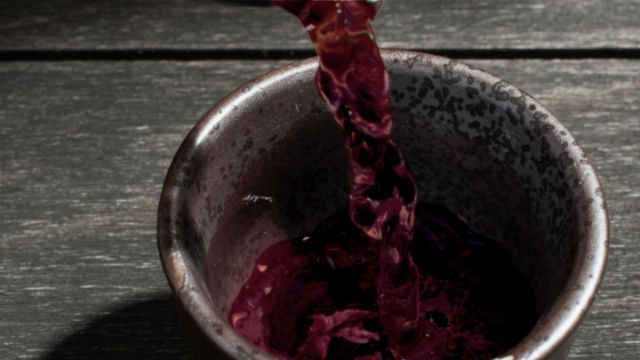 A stream of dark red liquid pouring into a rustic ceramic bowl on an aged wooden surface, evoking scenes from timeless celestial observances or natural phenological cycles. Opens a new window with the video.