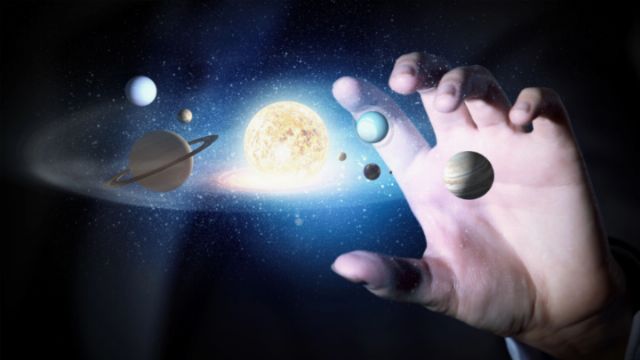 An artistic depiction of a human hand reaching towards a vibrant representation of the solar system with celestial bodies including the sun and several planets illuminated against a starry space background. Opens a new window with the video.